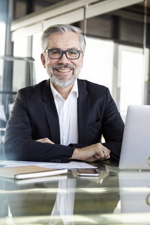 Porträt eines lächelnden Geschäftsmannes am Schreibtisch im Büro - RBF06327