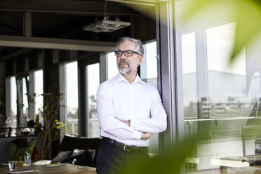 Businessman standing at French door thinking - RBF06330