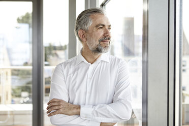 Portrait of smiling businessman looking out of window - RBF06336