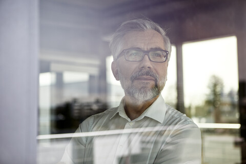 Portrait of businessman looking out of window stock photo