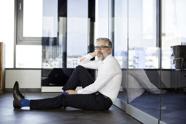 Geschäftsmann sitzt auf dem Boden im Büro - RBF06350