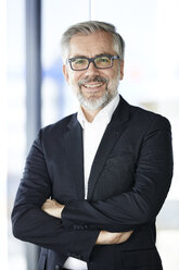 Portrait of smiling businessman standing at the window - RBF06353