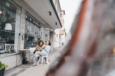 Zwei lachende Freunde sitzen vor einem Coworking Space - KNSF04049