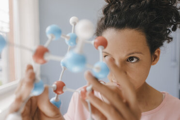 Female scientist holding molecule model, looking for solutions - KNSF04055