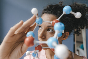 Female scientist holding molecule model, looking for solutions - KNSF04060