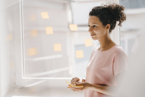 Frau klebt Haftnotizen ans Fenster, Brainstorming - KNSF04066