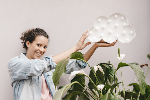 Lächelnde Frau hält Wolke über Zimmerpflanze - KNSF04083