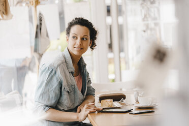 Junge Frau arbeitet im Coworking Space und isst Kuchen - KNSF04086