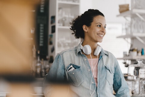 Junge Frau mit Kopfhörern, die in einem Coworking Space arbeitet, lizenzfreies Stockfoto