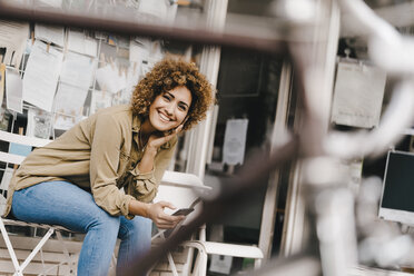 Woman in front of coffee shop, holding smart phone - KNSF04108