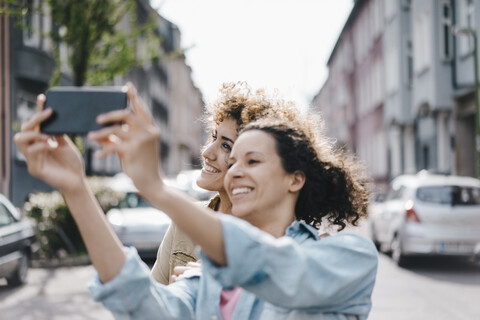 Beste Freunde machen Selfies mit einem Smartphone in der Stadt, lizenzfreies Stockfoto