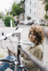 Woman in the city with headphones, using smartphone - KNSF04136