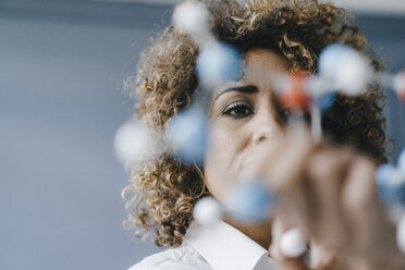 Female scientist looking at molecule model, looking for solutions - KNSF04156