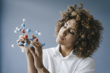 Female scientist looking at molecule model, looking for solutions - KNSF04157