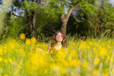 Young woman with closed eyes sitting on flower meadow - SARF03807