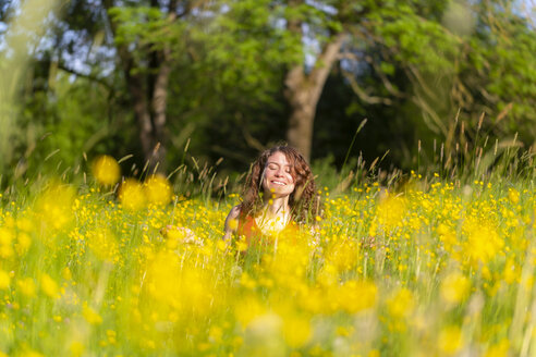 Junge Frau mit geschlossenen Augen auf einer Blumenwiese sitzend - SARF03807