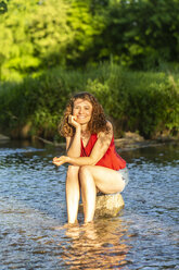 Junge Frau auf Stein sitzend, Fluss - SARF03808