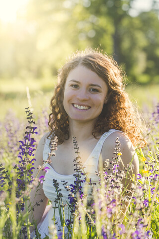 Junge Frau sitzt auf einer Sommerwiese, lizenzfreies Stockfoto