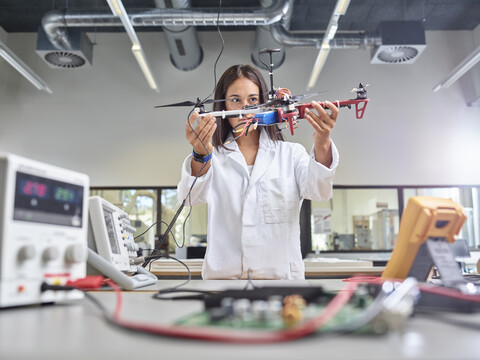 Technikerin arbeitet in einem Forschungslabor und hält eine Drohne, lizenzfreies Stockfoto
