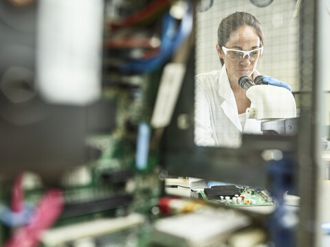 Technikerin bei der Arbeit mit dem Mikroskop im Forschungslabor, lizenzfreies Stockfoto