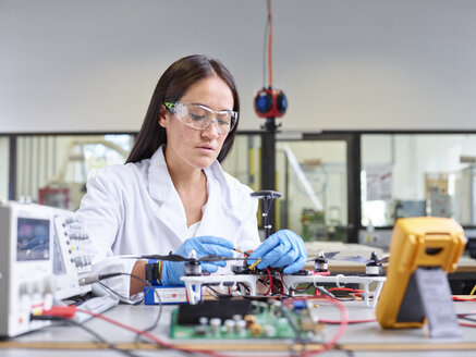 Technikerin bei der Arbeit im Forschungslabor, die den Stecker einer Drohne anschließt - CVF00889