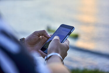 Hände benutzen Smartphone am Strand bei Sonnenuntergang - BEF00174