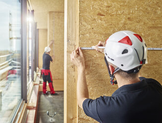 Worker with helmet marking with pencil on flakeboard - CVF00896