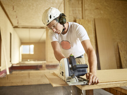 Worker with helmet sawing wood with circular saw - CVF00898