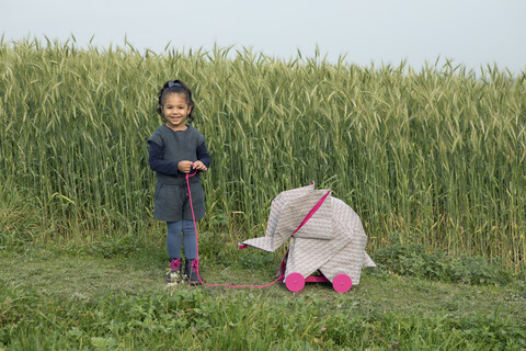 Kleines Mädchen mit Origami-Elefant auf einem Feld, lizenzfreies Stockfoto