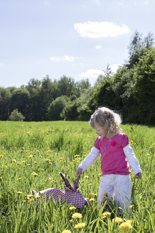 Kleines Mädchen mit Origami-Kaninchen auf der Wiese, lizenzfreies Stockfoto
