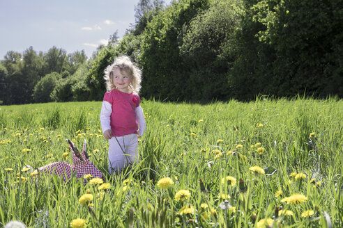 Kleines Mädchen mit Origami-Kaninchen auf der Wiese - PSTF00164