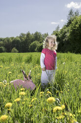 Kleines Mädchen mit Origami-Kaninchen auf der Wiese - PSTF00165