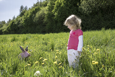 Kleines Mädchen mit Origami-Kaninchen auf der Wiese - PSTF00167