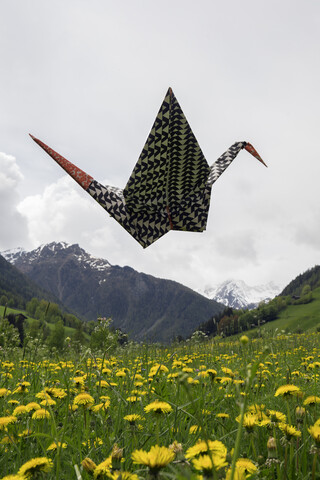 Origami-Kranich fliegt über Wiese, lizenzfreies Stockfoto