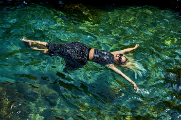 Junge Frau schwimmt mit Kleid auf dem Wasser in einer Lagune - BEF00175