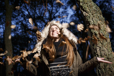 Young woman scattering leaves into air - CUF34505