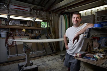 Porträt eines reifen Mannes in seiner Garage mit Surfbrettern - CUF34521