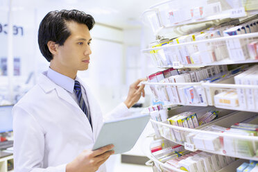Male pharmacist stock taking in pharmacy - CUF34541