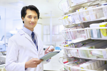 Portrait of male pharmacist stock taking in pharmacy - CUF34542