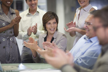 Mature businessman and colleagues celebrating in office - CUF34555