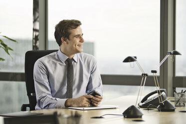 Young businessman sitting at desk in office - CUF34593