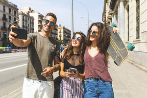 Drei glückliche Freunde machen ein Selfie in der Stadt - WPEF00443