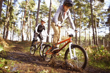 Zwillingsbrüder fahren mit BMX-Rädern durch den schlammigen Wald - CUF34660