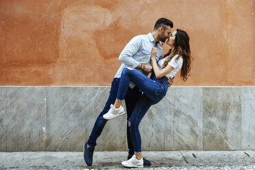 Verliebtes Paar küsst sich vor einer Mauer im Freien - JSMF00306