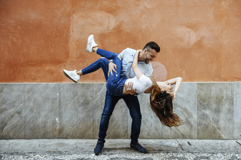Unbeschwertes verliebtes Paar vor einer Mauer im Freien, lizenzfreies Stockfoto