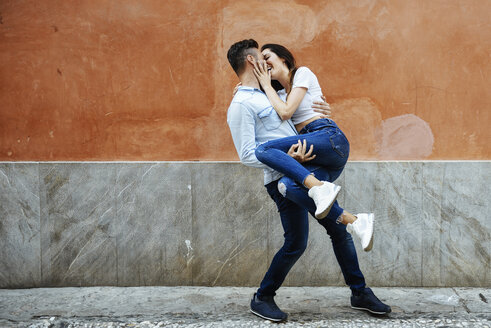 Carefree couple in love in front of a wall outdoors - JSMF00308
