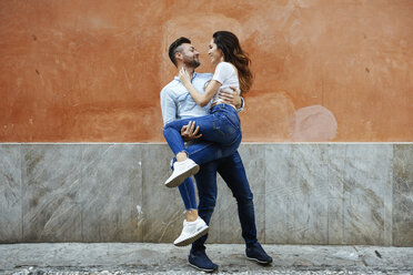 Carefree couple in love in front of a wall outdoors - JSMF00309
