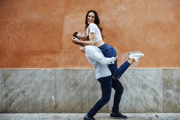 Carefree couple in love in front of a wall outdoors - JSMF00310