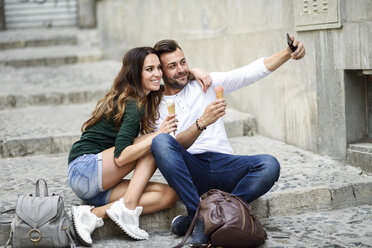 Tourist couple with ice cream cones in the city taking a selfie - JSMF00322