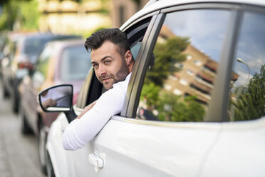 Mann lehnt sich aus dem Fenster seines Autos in der Stadt - JSMF00339